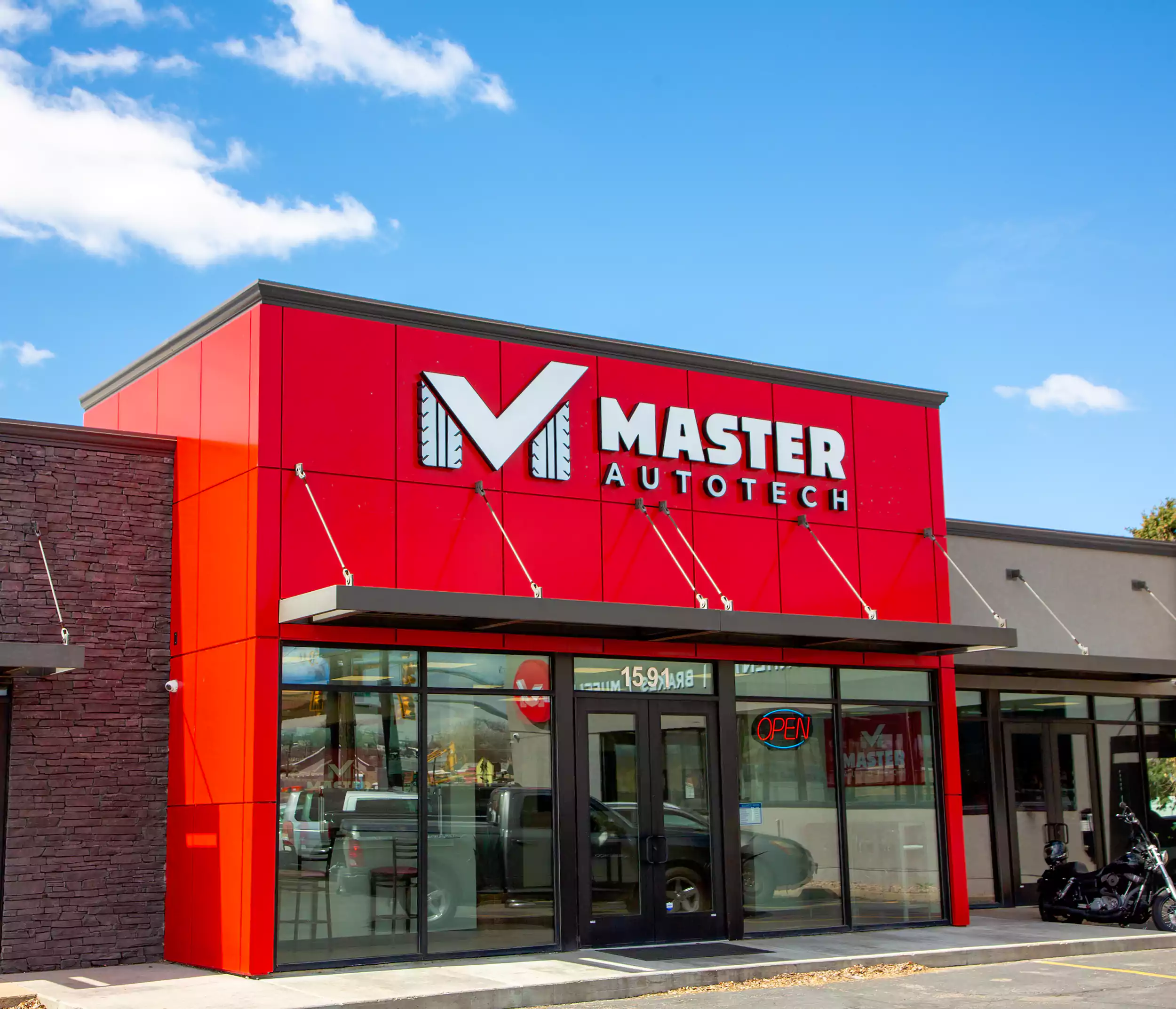 Master AutoTech storefront featuring bold red exterior, large logo, and "OPEN" sign, emphasizing franchise opportunity in the automotive service industry.